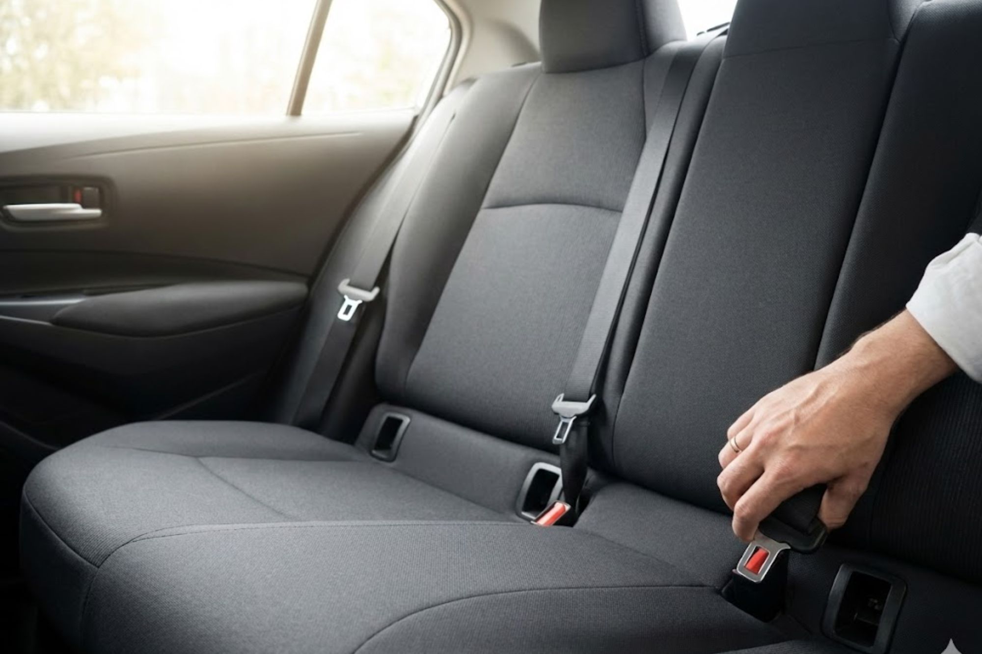 Persona ajustando el cinturón de seguridad en el asiento trasero de un automóvil moderno