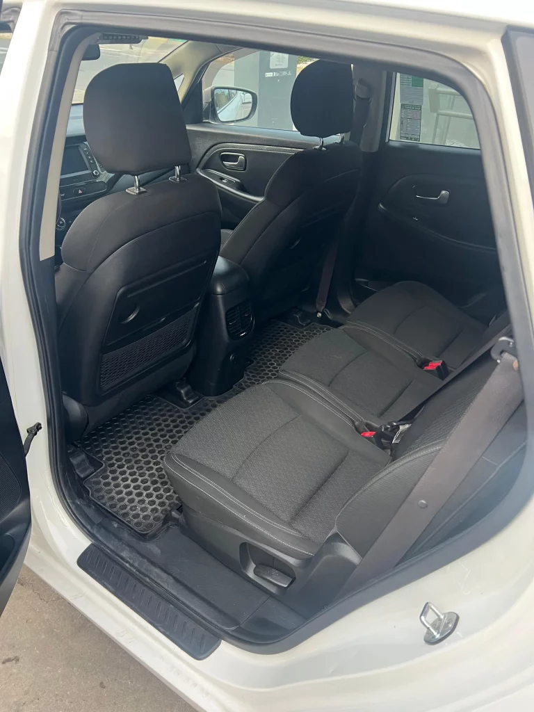 Vista del interior trasero de un SUV moderno con asientos de tela negra y alfombrillas de goma.